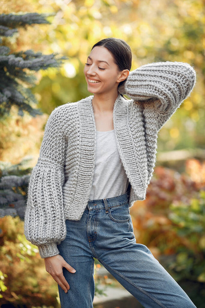 Girl in a kniten sweater standing on trees background - Фото, изображение