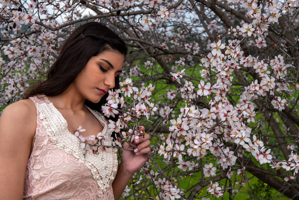Atrakcyjna młoda piękna dama, ubrana w różową odzież, pachnąca kwiatami śliwki. Koncepcja wiosennego powitania - Zdjęcie, obraz