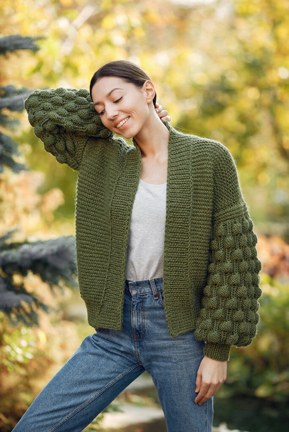 Girl in a kniten sweater standing on trees background - Fotó, kép