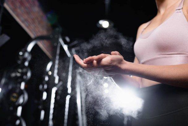 vista ritagliata della sportiva che applica talco in polvere sulle mani nel centro sportivo - Foto, immagini