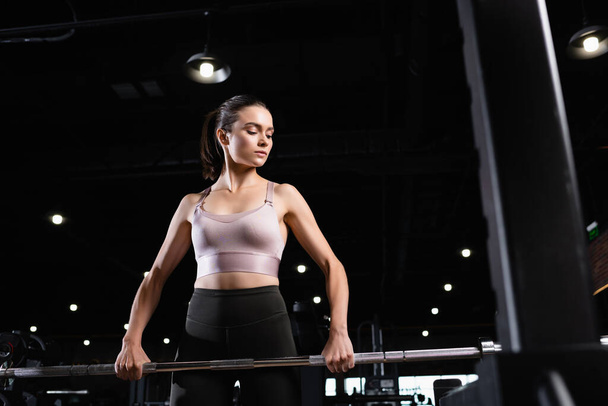 athletic woman in sports bra training with power rack in sports center - Фото, зображення