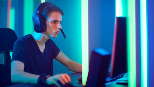 Young Pro Gamer Playing in Online Video Game, talks with Team Players through Microphone. Neon Colored Room. e-Sport Cyber Games Internet Championship. - Фото, изображение