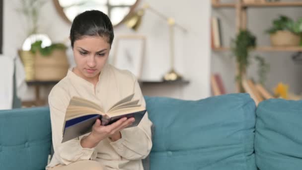 Young Indian Woman Sitting Reading Book on Sofa  - Video, Çekim
