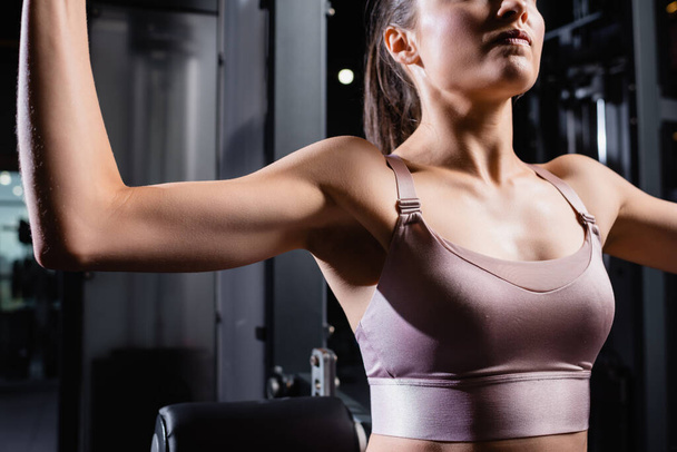 cropped view of sportive woman in sports bra training in gym - Foto, Imagen