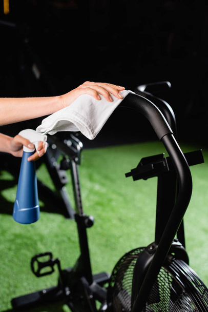 cropped view of charwoman wiping exercising machine in sports center - Photo, Image