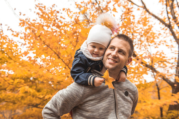 A portrait of a father with child in the autumn park - Foto, imagen