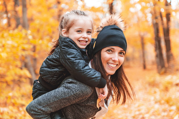 A portrait of a mother with child in the autumn park - Photo, Image