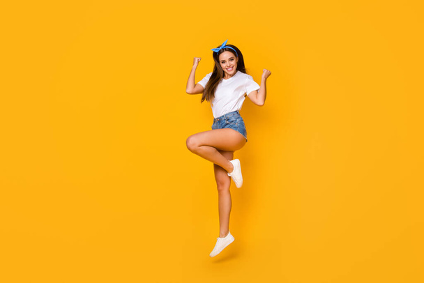 Full size photo of cheerful crazy girl win spring discount lottery jump raise fists wear good look lifestyle outfit shoes blue headband isolated over bright color background - Foto, afbeelding