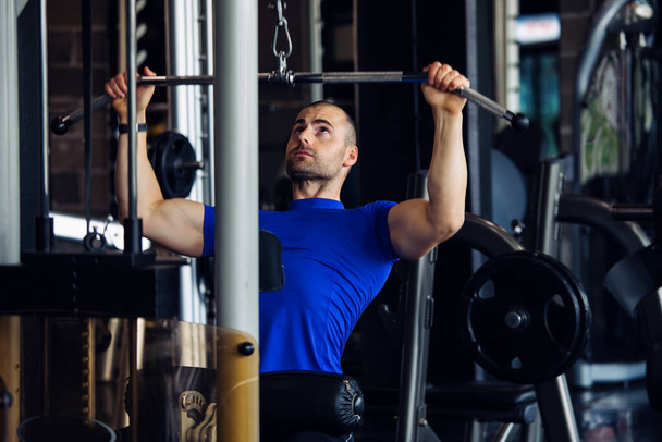 Bodybuilder working out in gym with determination - Valokuva, kuva