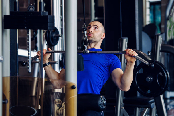 Fit man exercising at the gym on a machine. - Valokuva, kuva