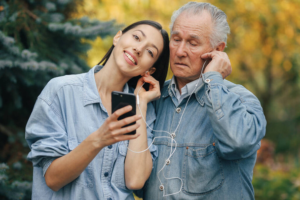 Girl teaching her grandfather how to use a phone - Valokuva, kuva