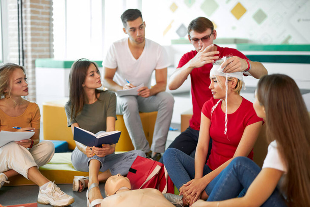 young confident male safety instructor teach students to bandage the head - Fotoğraf, Görsel