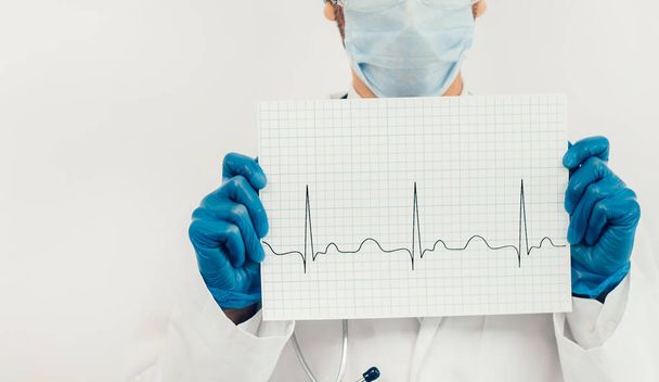sheet with a cardiogram in the hands of a doctor. - Фото, изображение