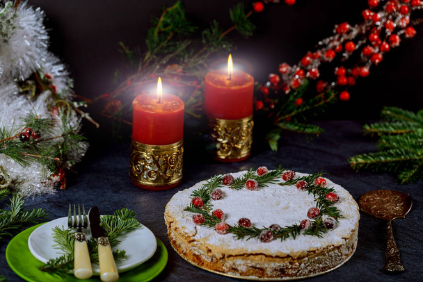 Karácsony este ünnepi tortával és égő gyertyákkal, áfonyával és fenyőágakkal díszítve. Üdülési koncepció. - Fotó, kép
