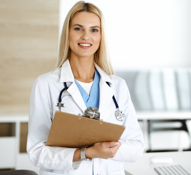 Doctor woman at work in hospital controls medication history records and exam results while using clipboard. Medicine and healthcare concept - Φωτογραφία, εικόνα