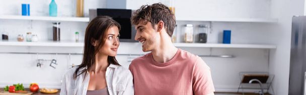 Smiling man looking at girlfriend in kitchen, banner - Фото, изображение