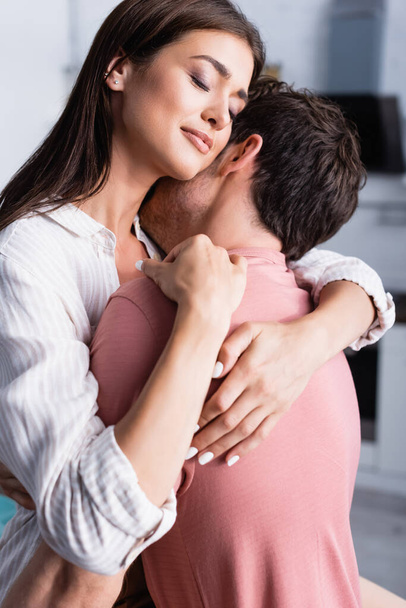 Молодая женщина обнимает парня с закрытыми глазами дома  - Фото, изображение