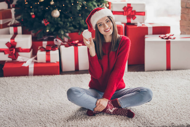 Photo of lovely lady sit carpet gift boxes play pompon wear santa headwear red pullover socks jeans in decorated x-mas living room indoors - Photo, image