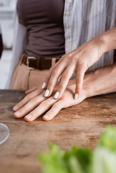 Cropped view of woman touching hand of boyfriend on kitchen table  - Photo, Image