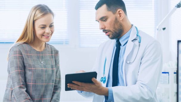 Beautiful Female Visits Doctors Office, He Shows Tablet Computer with Her Medical History They Discuss Her Health and Other Medical Issues. Modern Medical Office. - Photo, image