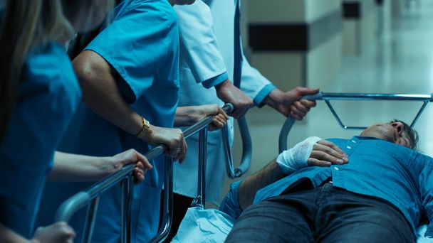 Service d'urgence : Médecins, infirmières et chirurgiens poussent la civière Gurney avec un patient gravement blessé vers la salle d'opération. - Photo, image