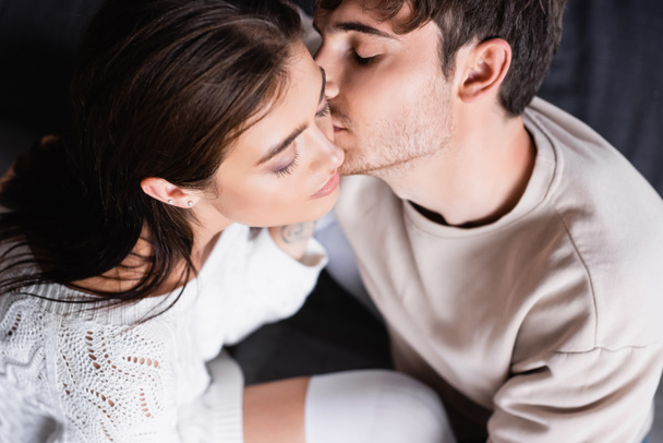 Overhead view of man kissing girlfriend at home  - Zdjęcie, obraz