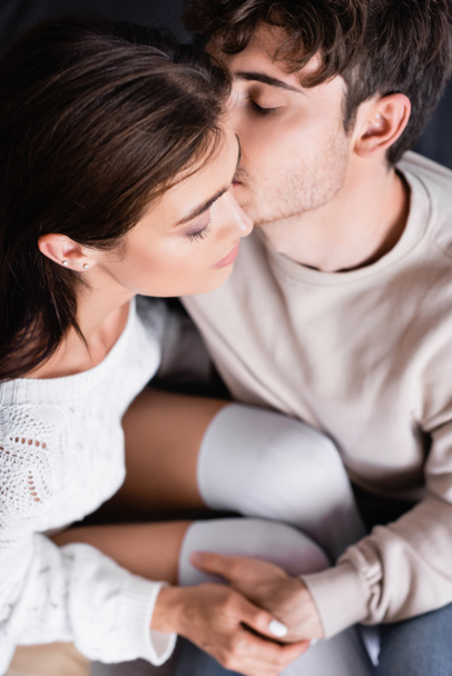 Overhead view of man with closed eyes kissing girlfriend at home  - Foto, afbeelding