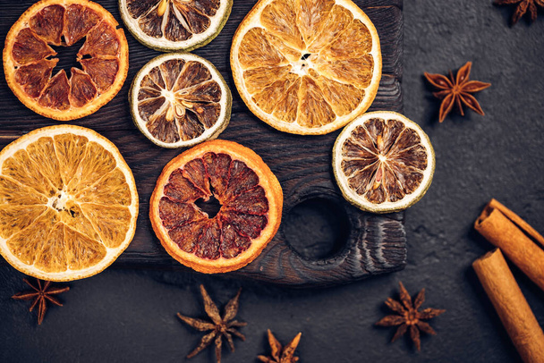 Dried citrus fruits composition with orange, lime, anise and cinnamon sticks. Dark natural wooden background. Creative christmas concept. - Fotoğraf, Görsel