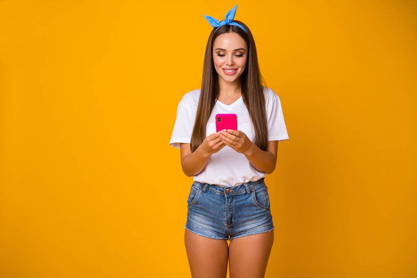 Portrait of positive cheerful girl use cellphone read social network news enjoy comment posts subscribe wear white t-shirt denim blue headband isolated over bright shine color background - Foto, Imagen