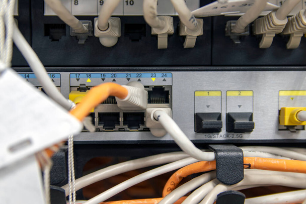 Netwerkhardware. Optische vezel. Witte kabels verbinden met netwerkapparatuur. Server close-up. Fragment van serverapparatuur. Selectieve focus. - Foto, afbeelding