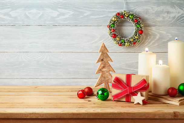Christmas holiday background with gift box, ornaments and candle decor on wooden table. Winter greeting card. - Fotó, kép