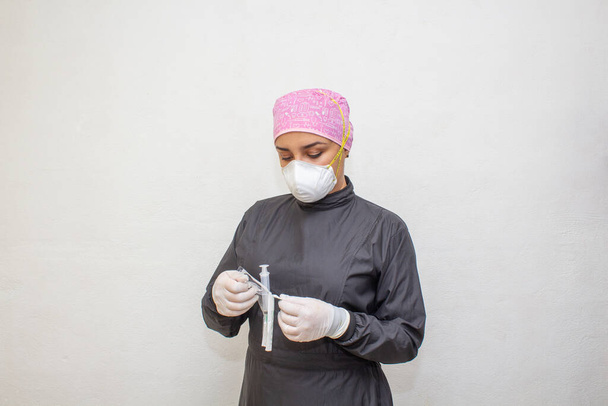 female doctor or dentist in surgical suit with opening syringe. - Photo, Image