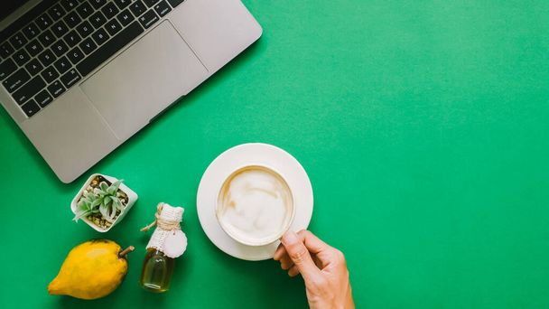 Portátil digital con maceta de árbol, botella de miel, taza de café y canistel o fruta de huevo en papel verde - Foto, imagen