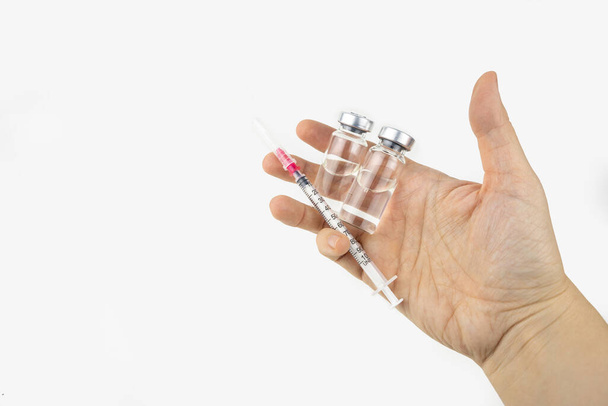 注射治療のための手の中に薬と注射器を持つ2つのバイアル。Covid-19ワクチンの概念。白地に隔離された - 写真・画像
