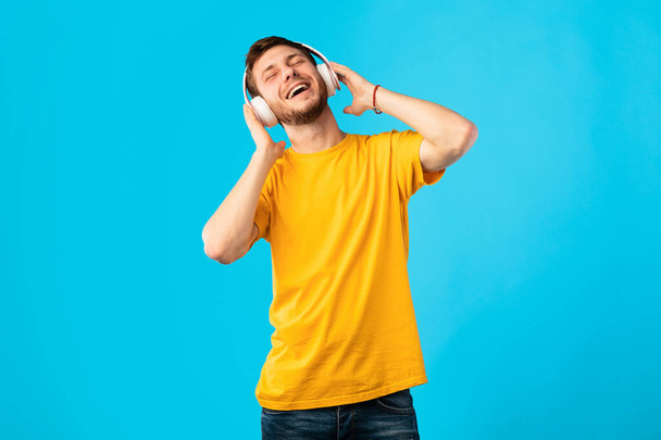 Uśmiechnięty mężczyzna cieszący się muzyką ze słuchawkami i tańcem - Zdjęcie, obraz