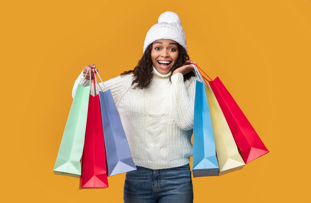 Sonriente mujer negra llevando bolsas de compras en el estudio - Foto, Imagen