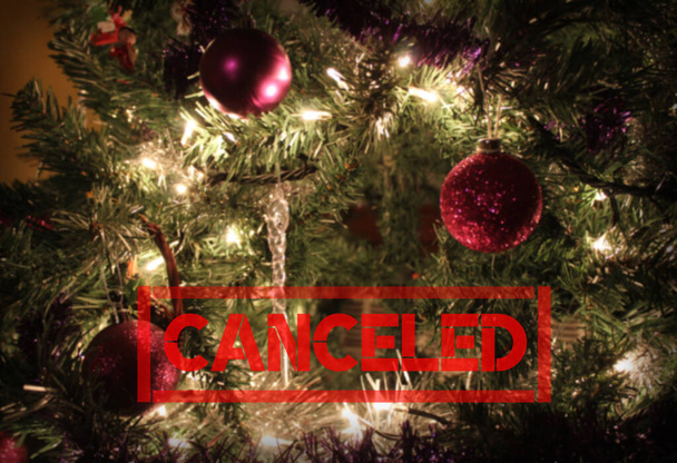 Texto 'Cancelado' vermelho em um fundo de árvore de Natal decorado borrado com copyspace. Temporada de férias conceito cancelado devido ao vírus Corona ou outras razões. - Foto, Imagem