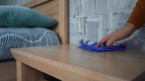man veegt een doek op het nachtkastje in de slaapkamer - Video