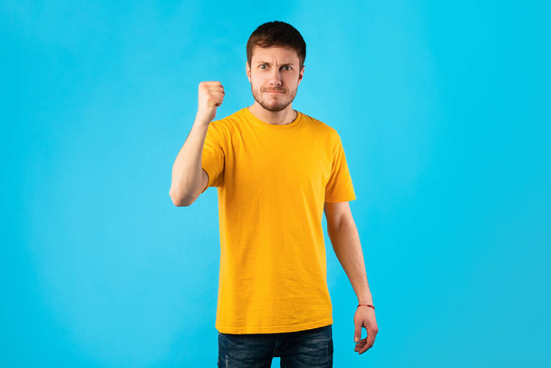 Young handsome man shaking clenched fist to camera - Photo, Image