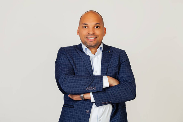 Portrait of successful young African American businessman guy, happy face, smiling with crossed arms, looking at camera. A positive person. Standing on a gray background. - Foto, imagen