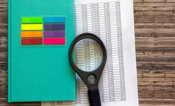 Carnet vert avec loupe, documents numérotés et autocollants colorés sur table en bois - Photo, image