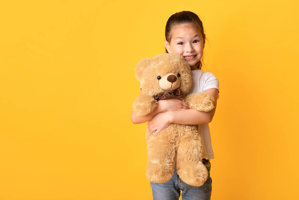 Kleine asiatische Mädchen stehen und halten Teddybär - Foto, Bild