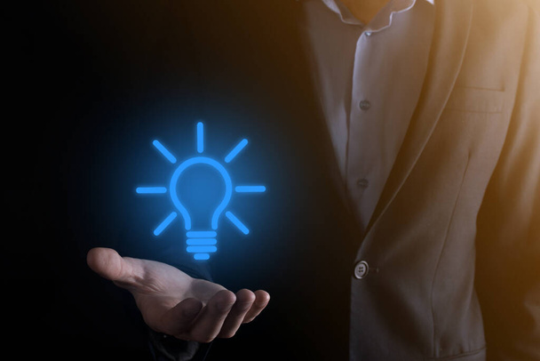 Businessman in a suit with a light bulb in his hands. Holds a glowing idea icon in his hand. With a place for text. - Photo, image