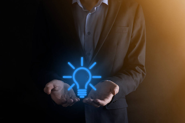 Businessman in a suit with a light bulb in his hands. Holds a glowing idea icon in his hand. With a place for text. - Photo, Image