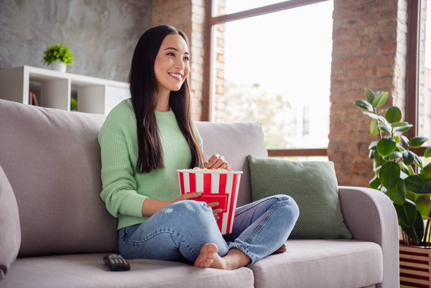 Profile side full body photo of nice satisfied cute chinese girl watch film bare foot have big pop corn box enjoy free time in house indoors apartment - Фото, зображення
