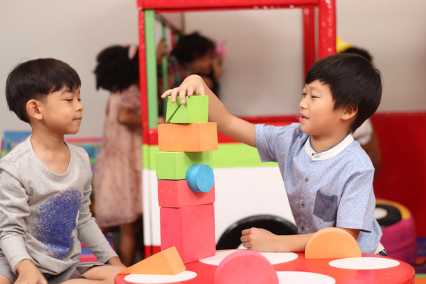 Счастливые веселые дети, веселящиеся на детской площадке, маленькие дети, играющие с друзьями, два азиатских мальчика, играющих вместе.  - Фото, изображение