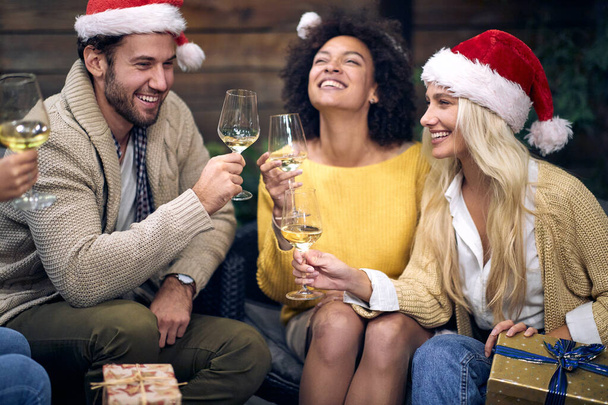 Group of young cheerful people enjoying champagne in festive atmosphere at christmas or new year party together. Xmas, friends, toast, fun, party concept - Photo, image