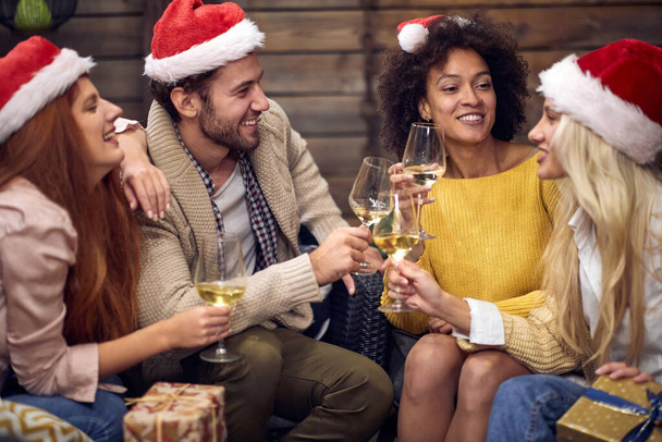 Group of cheerful people toasting at christmas or new year party in relaxed atmosphere together. Xmas, friends, toast, fun, party concept - Fotó, kép