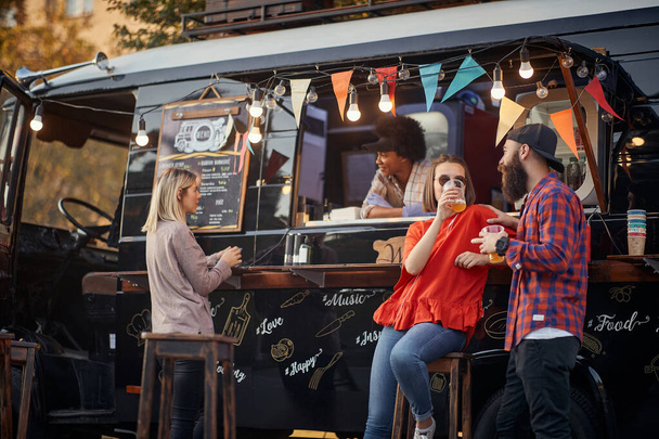 people socializing in front of truck food, drinking juices - Fotó, kép