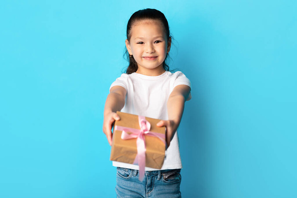 Счастливая азиатка дарит тебе подарочную коробку в голубой студии - Фото, изображение